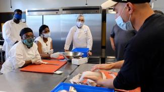 Culinary trainees learn proper fish cutting techniques.