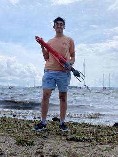 Intern holding a robotic device on the shoreline